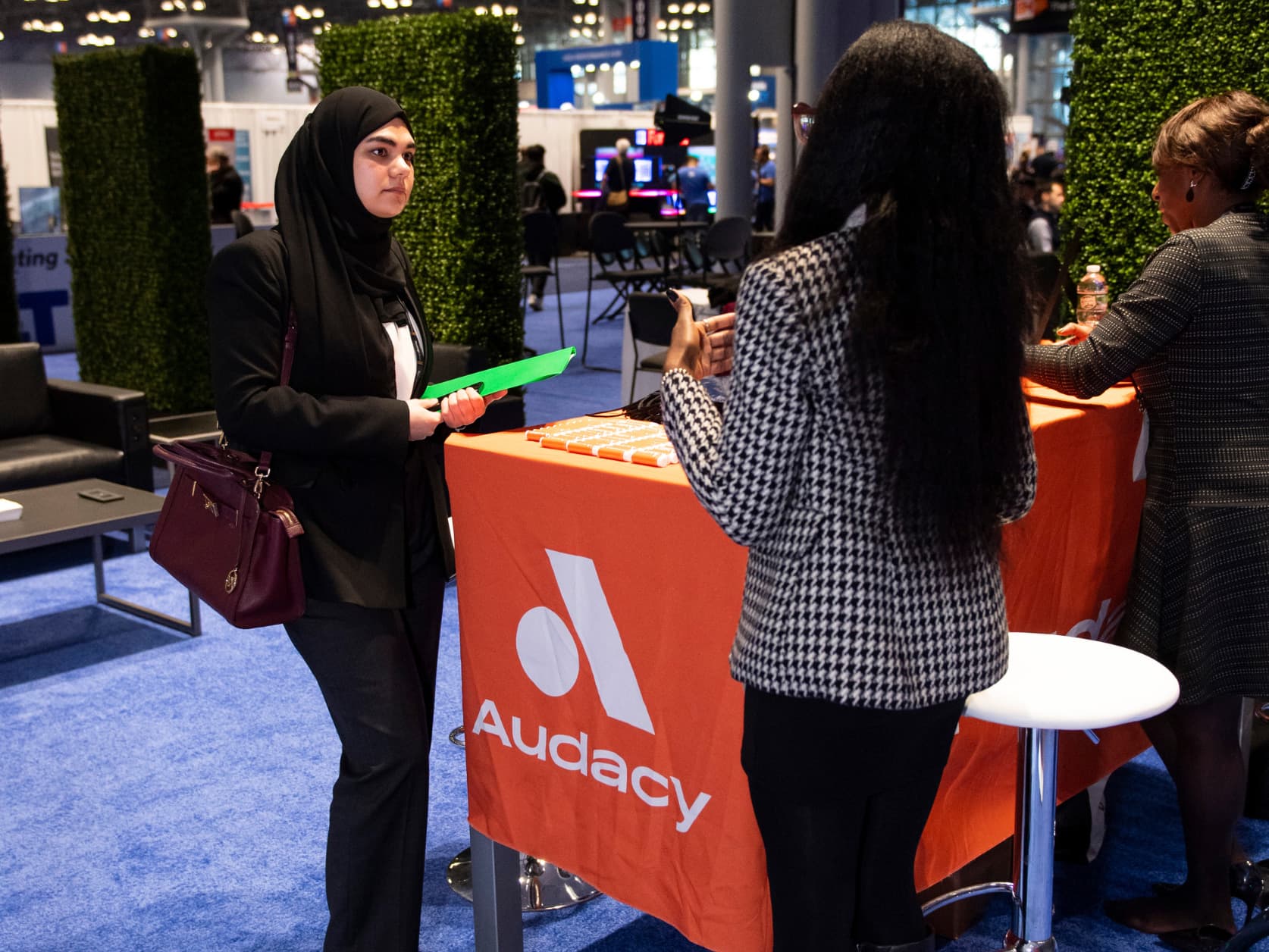 Two women are connecting over an exhibitor booth on the show floor.