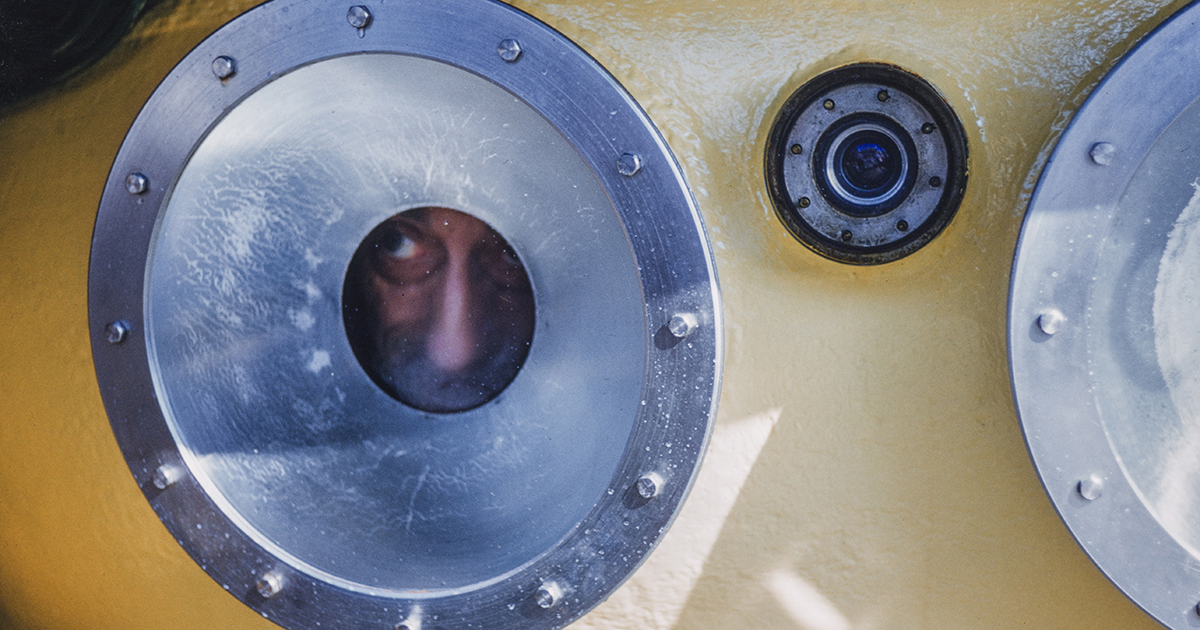 Jacques Cousteau peers out of the porthole of SP-350 Denise diving saucer, 1960. (Credit: National Geographic/Luis Marden)